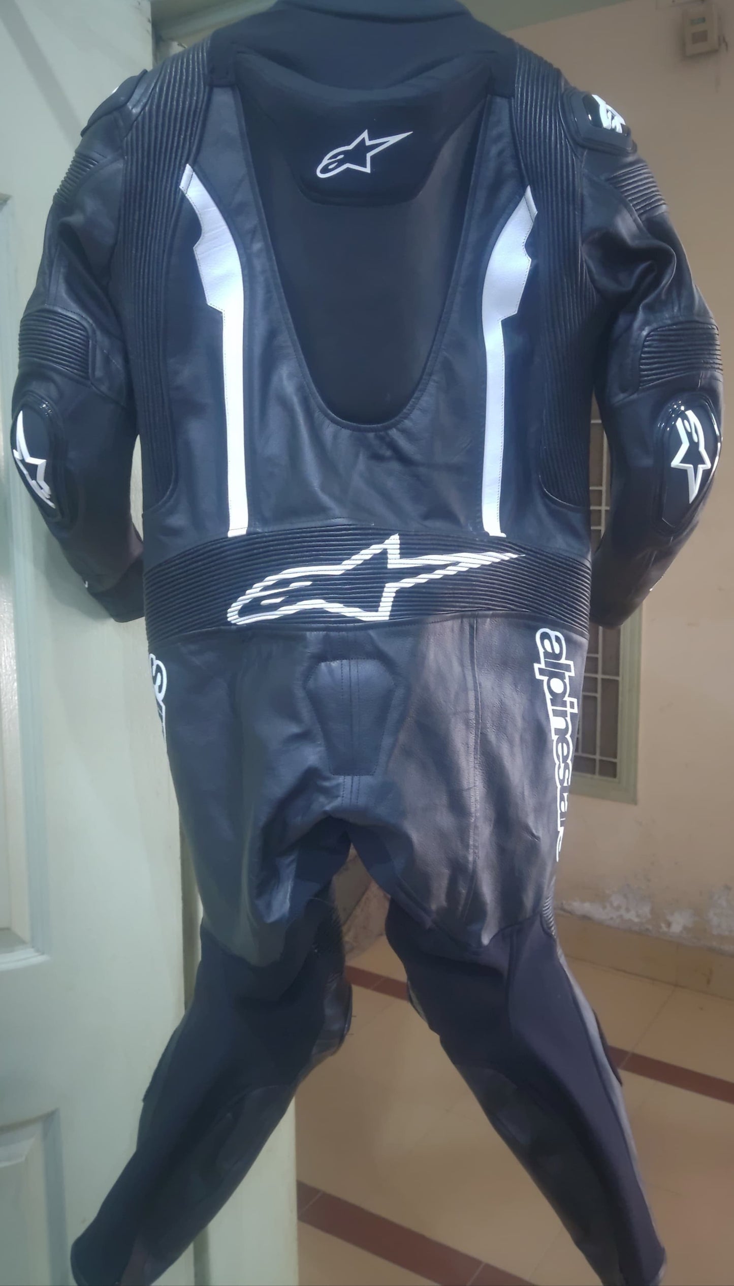Black motorcycle suit with visible branding on a plain background