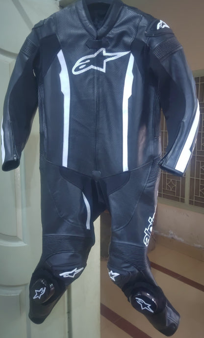 Black motorcycle suit with white accents on a stand against a neutral background