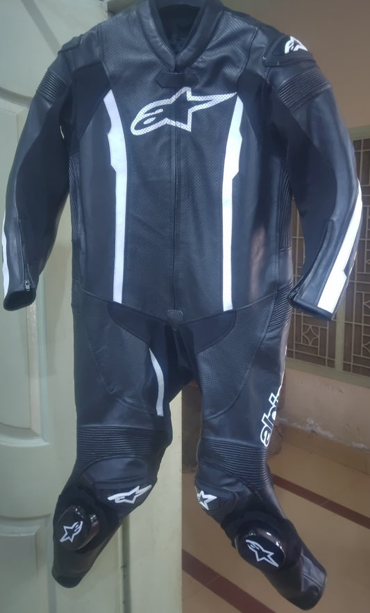 Black motorcycle suit with white accents on a stand against a neutral background