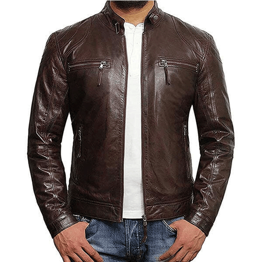 A man wearing a brown leather motorcycle jacket with a mandarin collar, embroidered leather applique graphics on the left arms, and front and back cowhide leather accents.